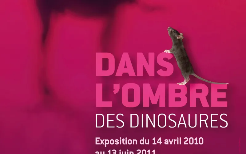 Affiche de l'exposition montrant une souris devant l'ombre d'un dinosaure.