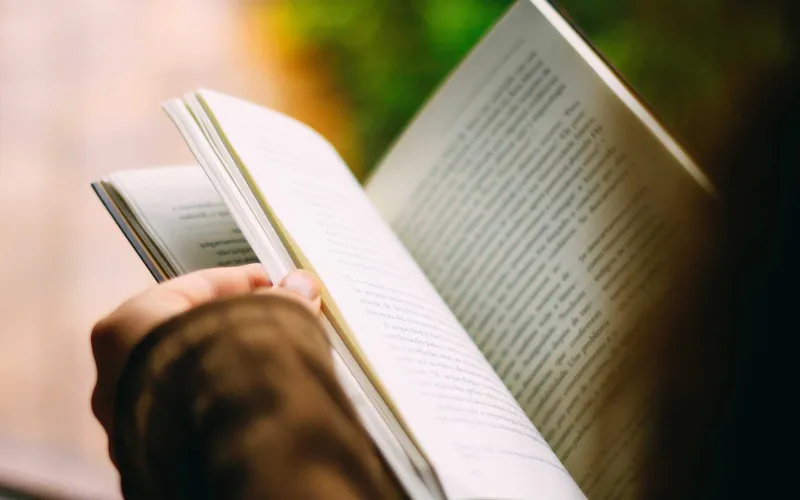 Des mains feuillettent un livre.